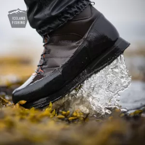 Durable wader boots with slip-resistant soles on a rocky riverbank.